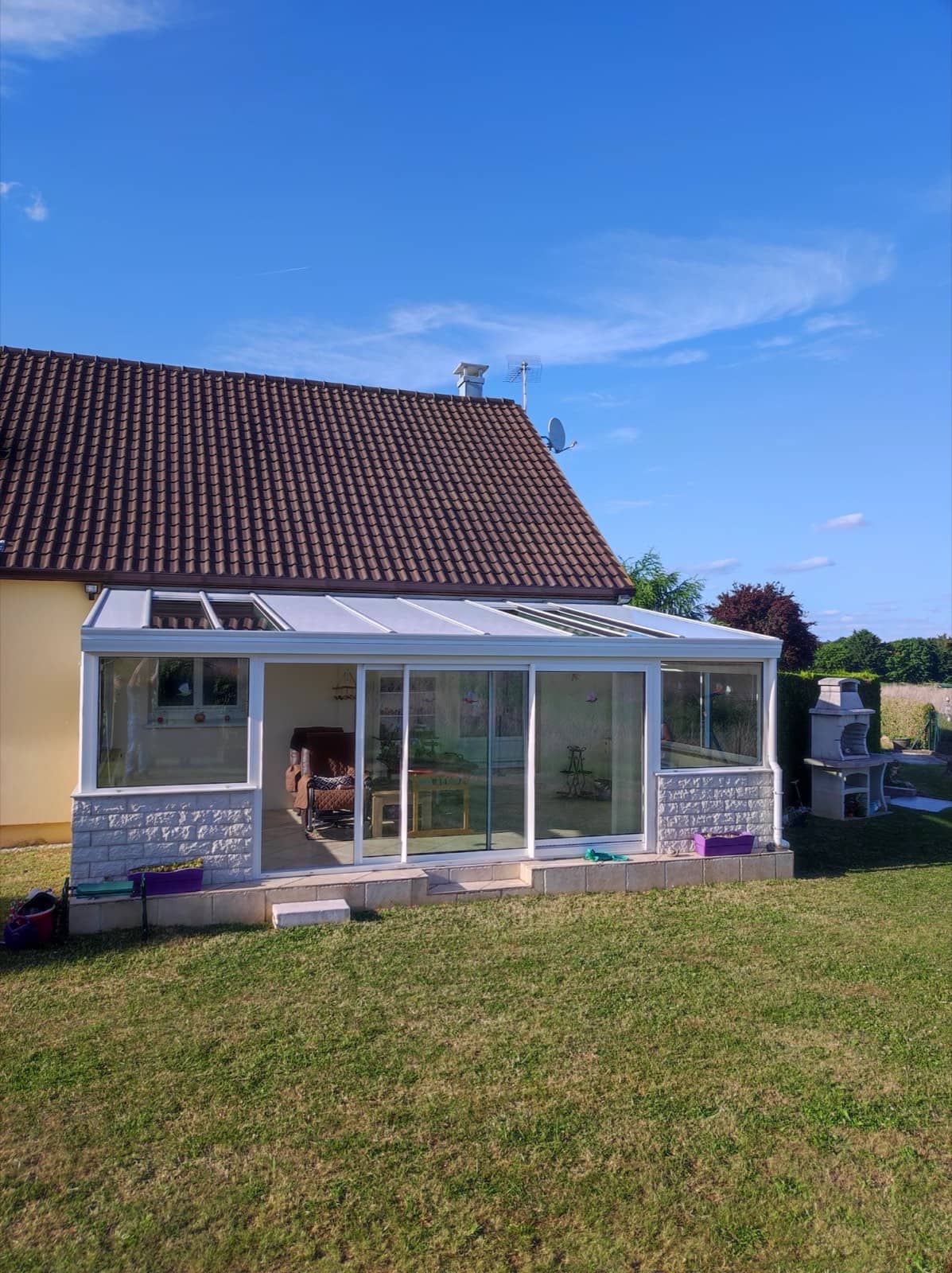 Véranda vitrée nettoyée accolée à une maison avec jardin